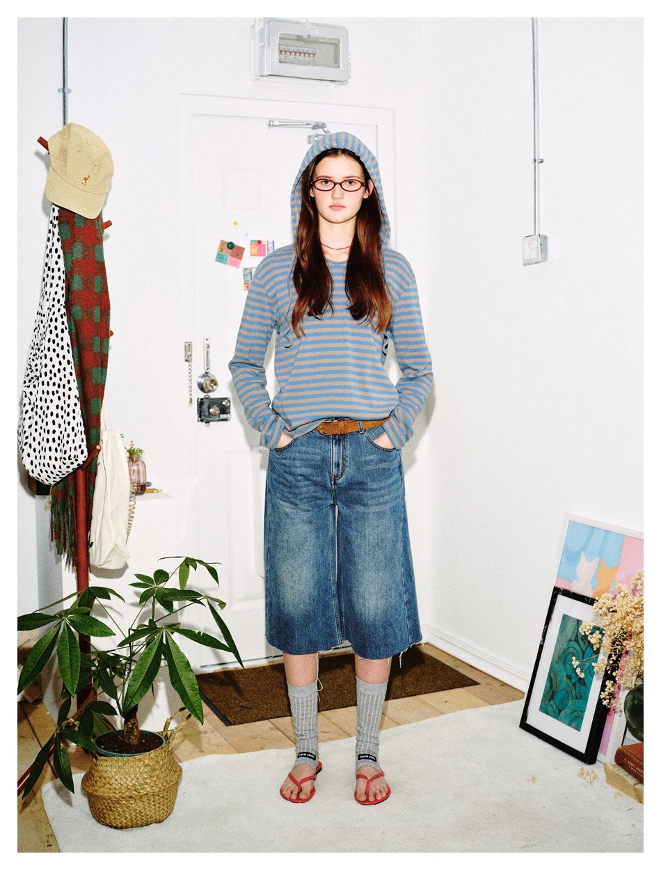 Front view of a model wearing a blue and taupe striped hooded top with wide-leg denim culottes and gray socks.