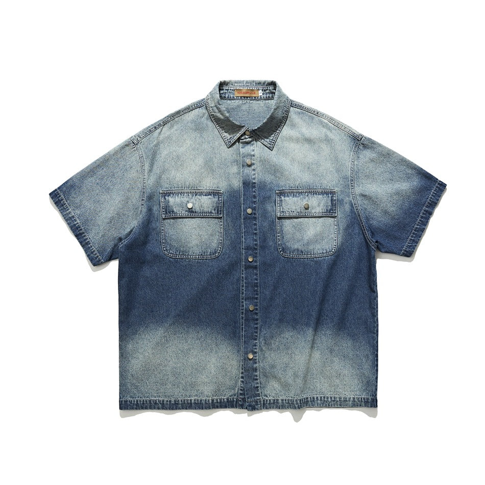 Washed blue denim short-sleeve shirt with two flap chest pockets and snap buttons, flat lay front view