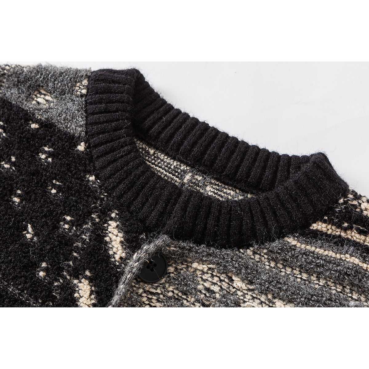 Close-up of a black ribbed crew neckline and button on a black, gray, and cream patterned knit sweater.