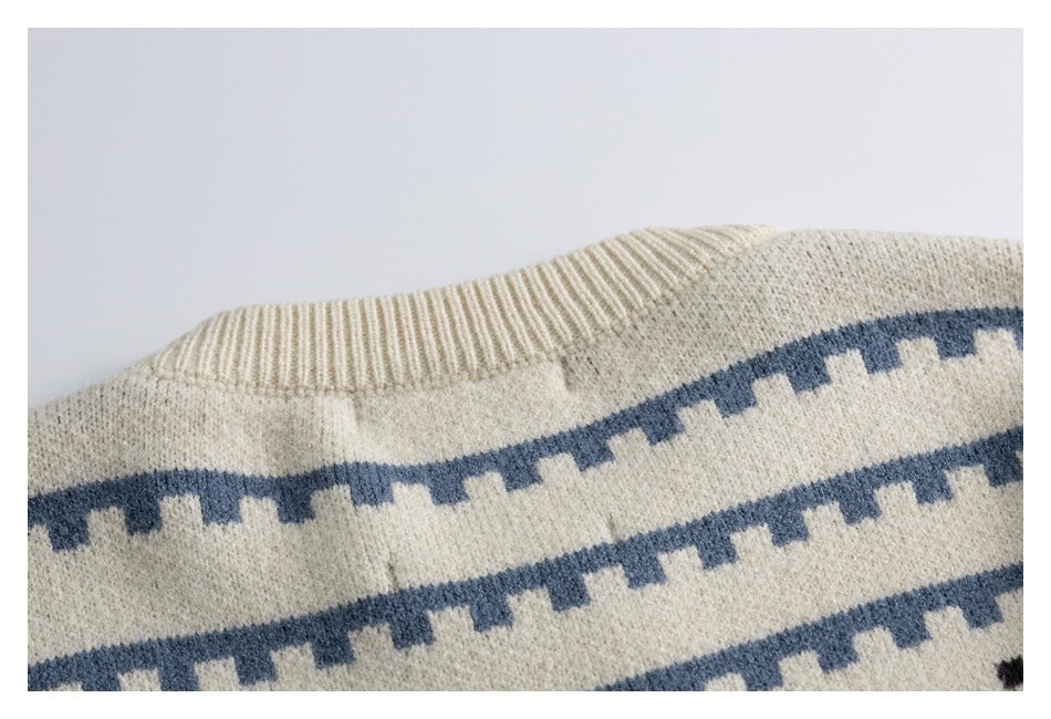 Close-up of an ivory ribbed neckline and shoulder with horizontal dusty blue geometric bands.