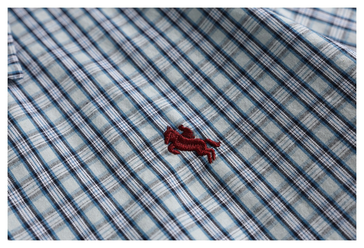 Close-up of a red embroidered animal logo on blue, gray, and white plaid fabric.