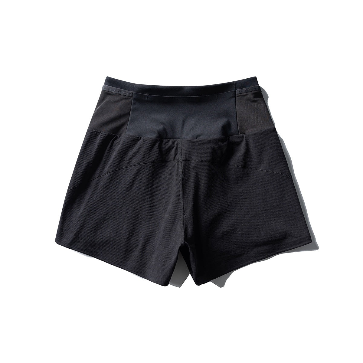 Black shorts with a wide waistband, smooth upper panels, and textured lower panels, shown from the front.