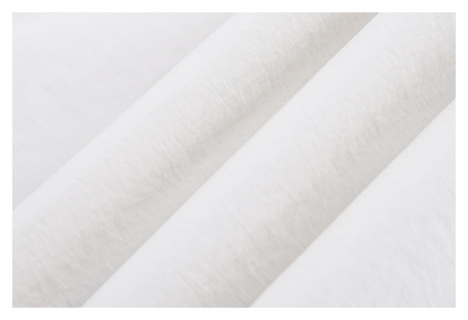 Close-up of white fabric showing a soft surface texture and diagonal folds.