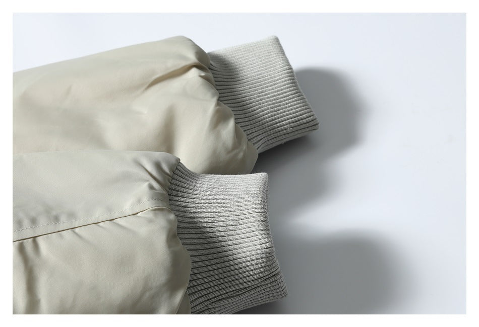 Close-up of light beige jacket sleeves ending in gray ribbed cuffs.