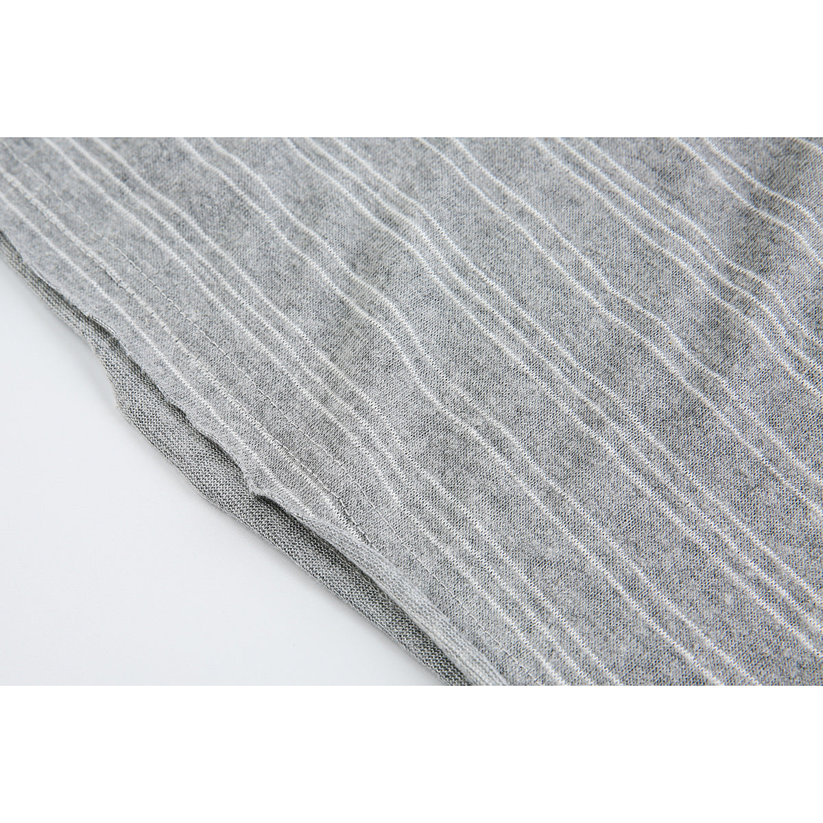 Close-up of a stitched edge on heather gray fabric with thin white stripes.