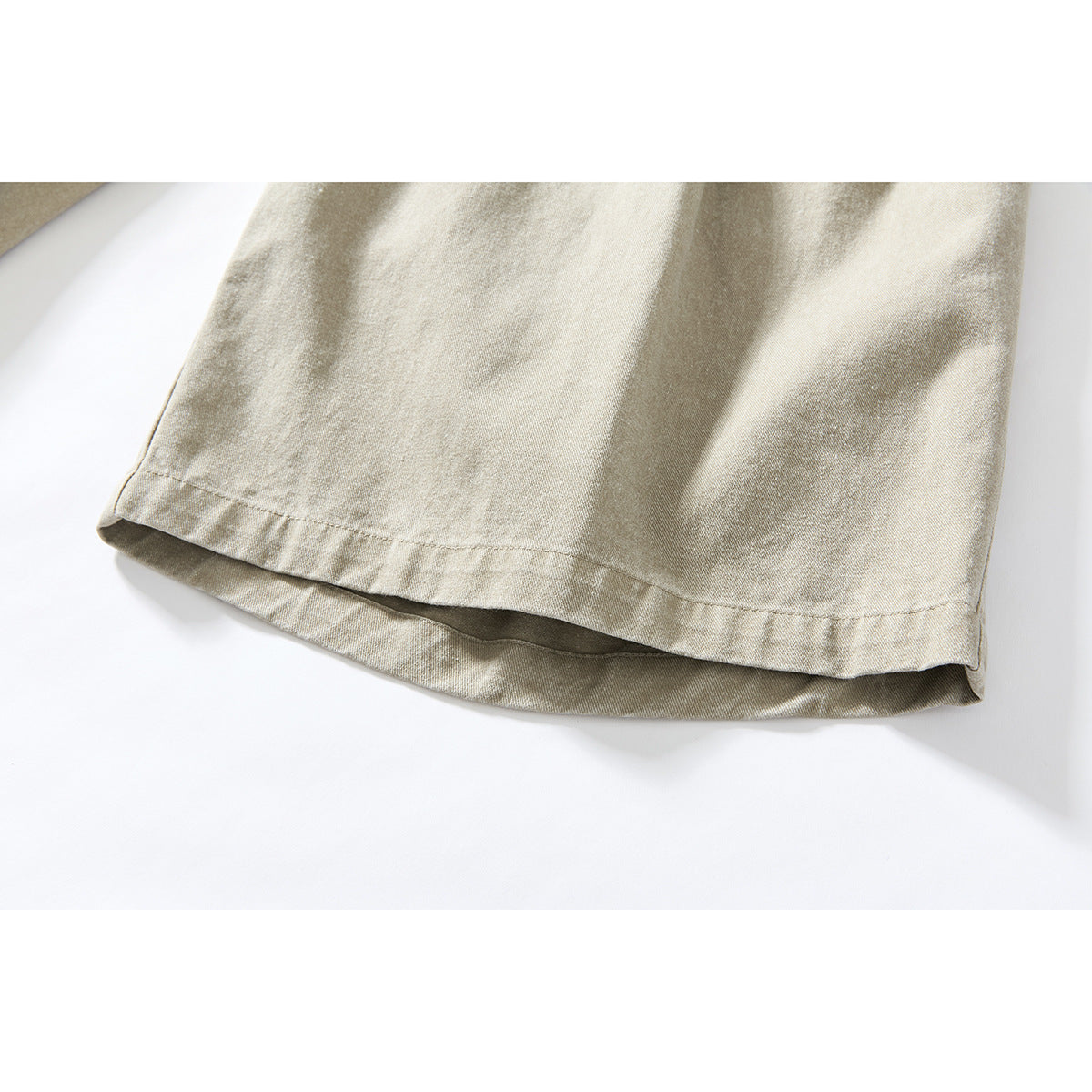 Close-up of the hem on beige wide-leg shorts, showing the stitching and washed, textured appearance.