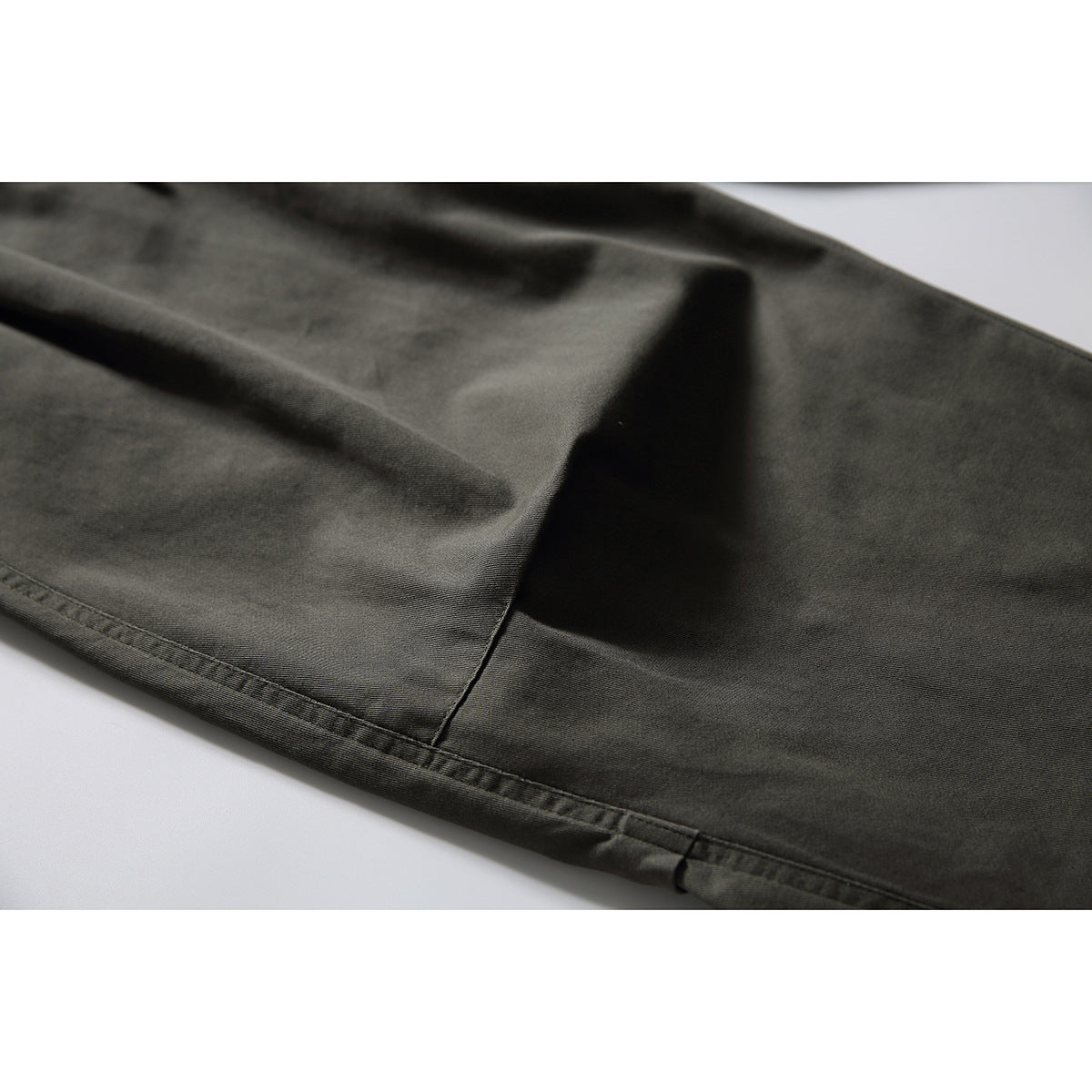 Close-up of the dark olive pants leg, showing the fabric and stitched hem.