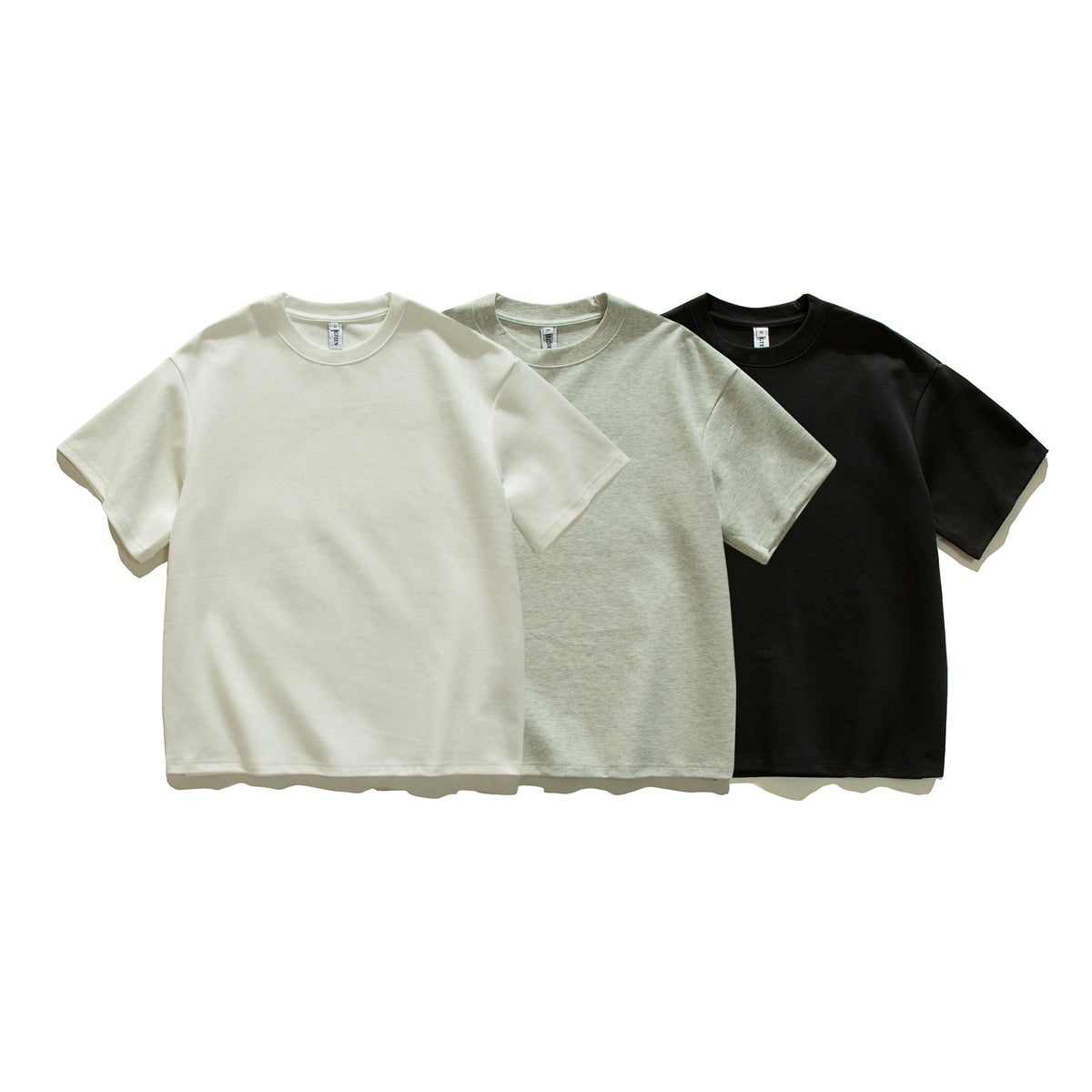 Three plain crew-neck T-shirts shown from the front in off-white, heather gray, and black.