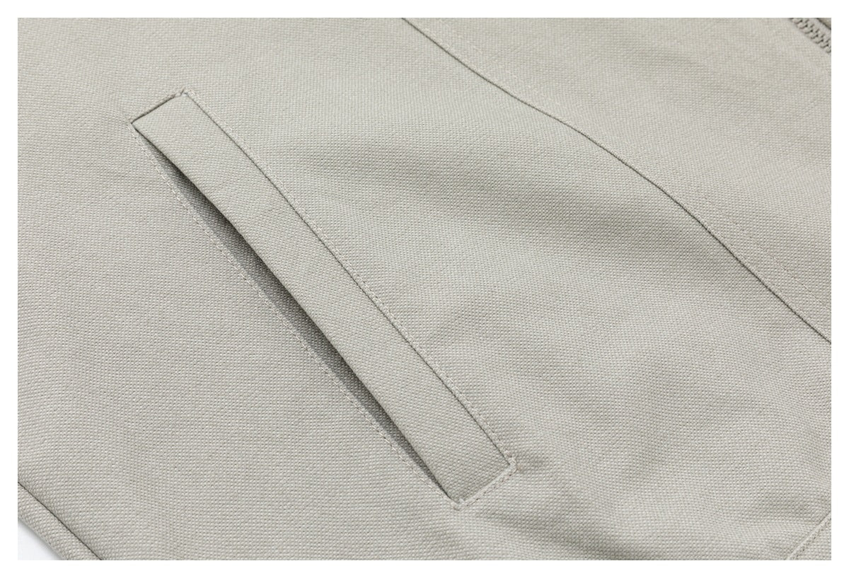 Close-up of a narrow stitched detail on the light beige jacket front.