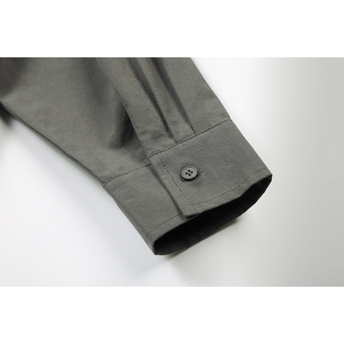 Close-up of a gray-green shirt sleeve cuff with a button closure.