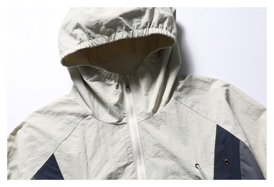 Close-up of an off-white hood and upper front of a jacket with a white zipper and dark contrast panels.