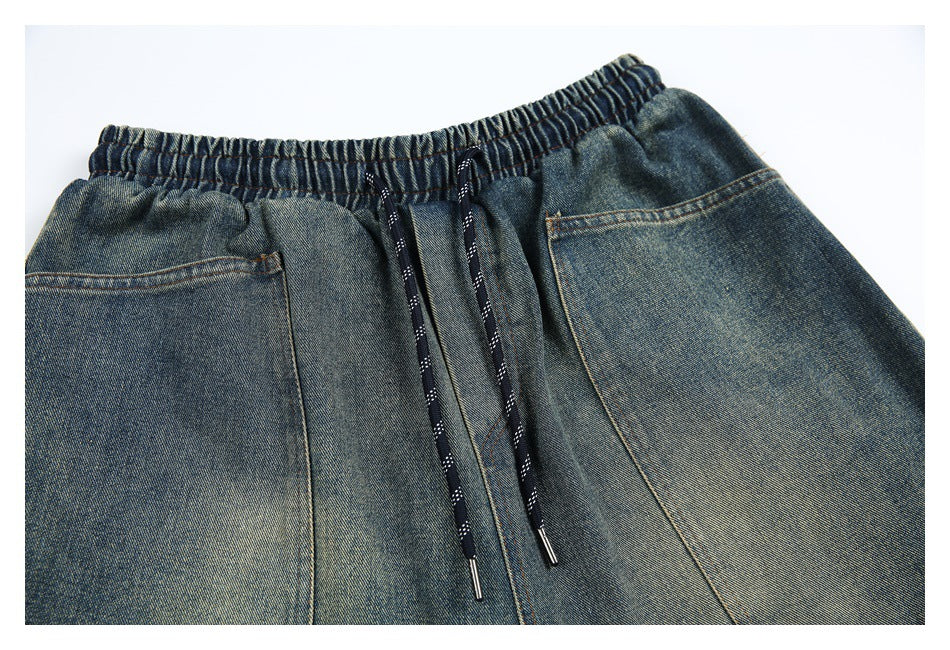 Front close-up of blue-gray denim shorts with an elastic waist, dark drawstrings, and large pockets.