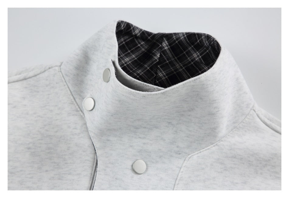 Close-up of a light gray marled jacket's high collar, plaid lining and round snap closures.