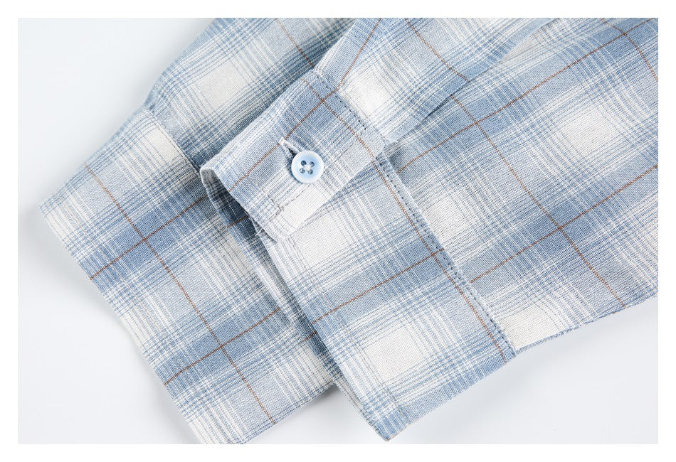 Close-up of a pale blue and white plaid shirt cuff with a white button.