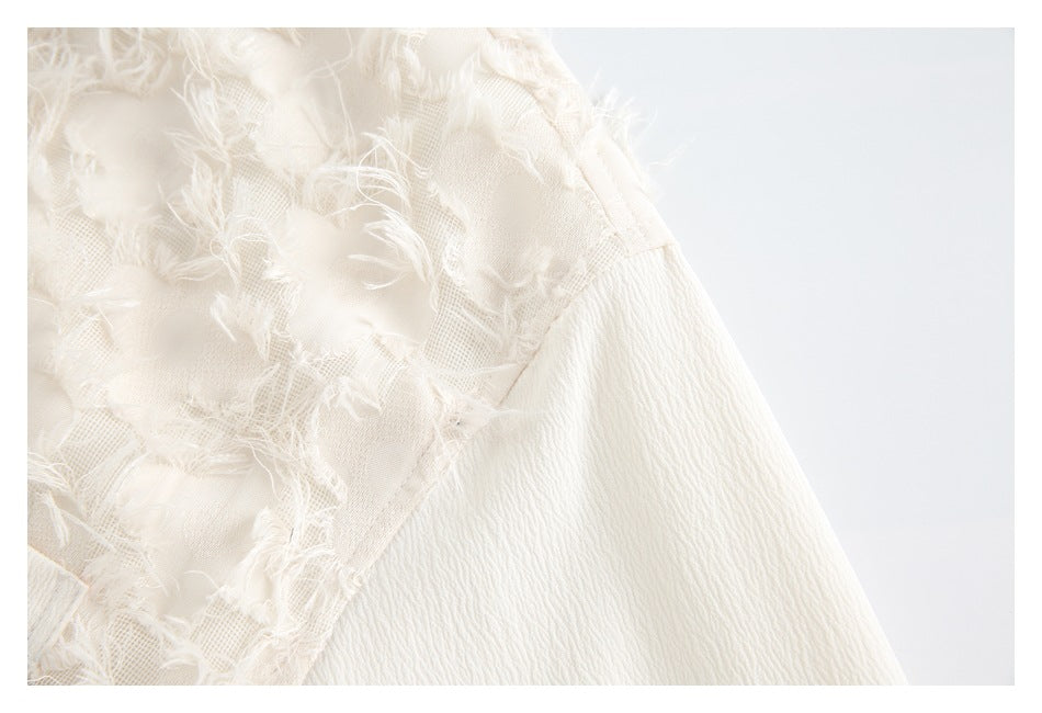 Close-up of white frayed floral appliqué meeting a textured sleeve seam.