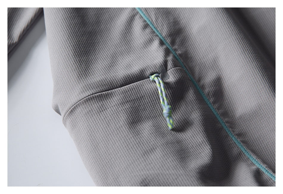Close-up of a pocket on the gray pullover with a multicolored cord pull and turquoise seam piping.