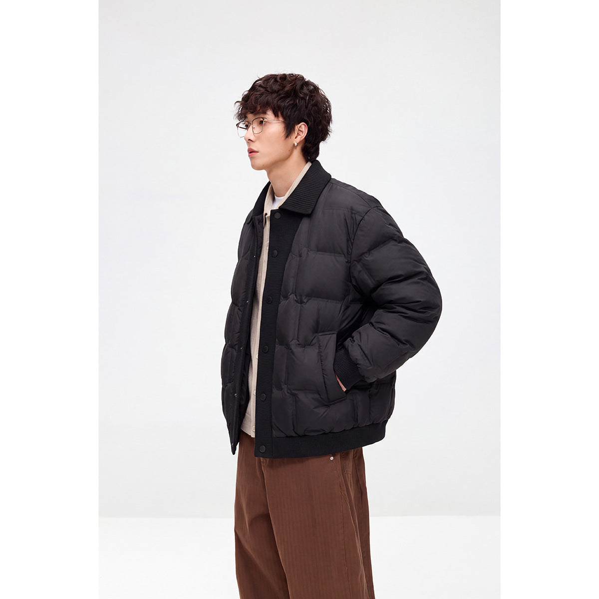 Model wearing a black quilted snap-front jacket with a ribbed collar and hem, shown at an angle.