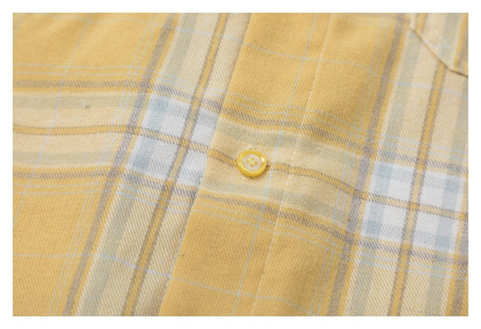 Close-up of a yellow button and the yellow, white, and gray plaid fabric.
