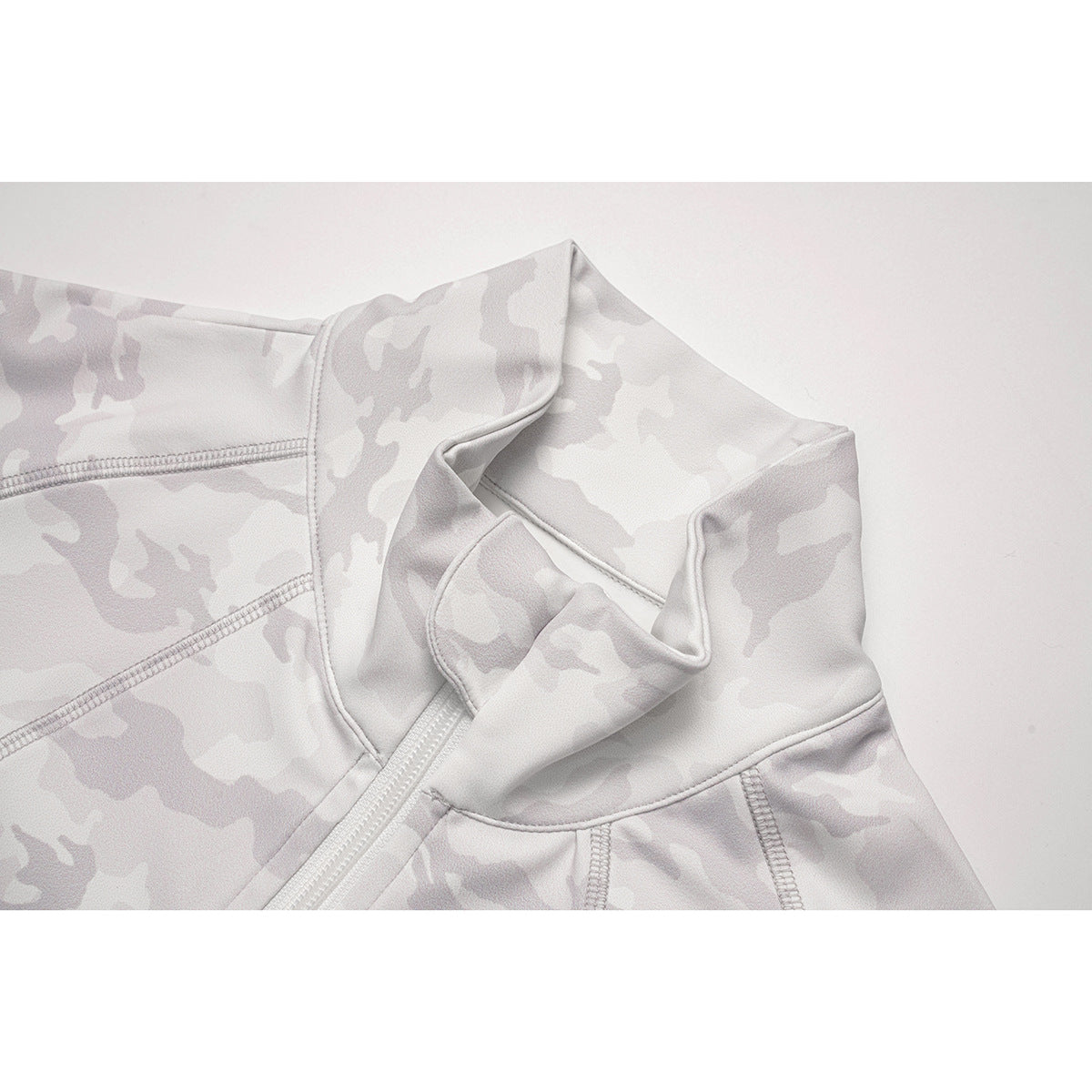 Close-up of the white camouflage jacket's stand collar, zipper, and stitched seams.
