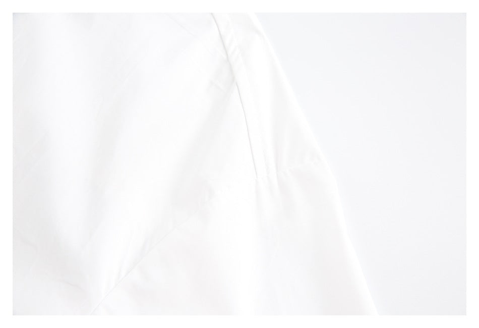 Overexposed close-up of white garment fabric with faint seams and folds.