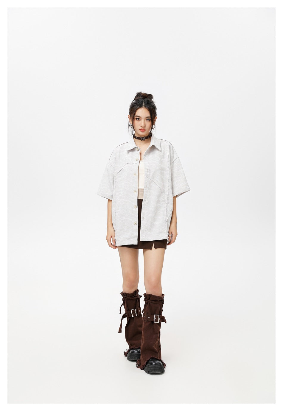 Model wearing the gray short-sleeve shirt open over a cream top with a brown mini skirt and buckled leg warmers