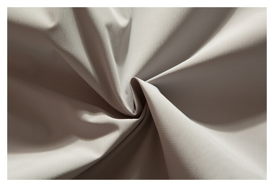 Close-up of light taupe fabric gathered into a twist, showing its subtle fine texture.