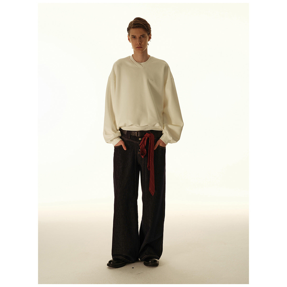 Model wearing an oversized cream crewneck sweatshirt with dark wide-leg jeans, front view.