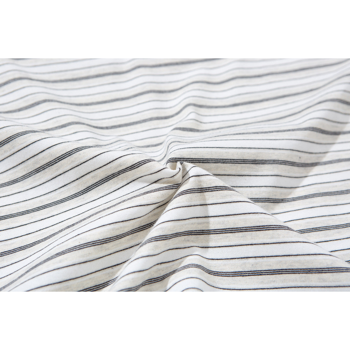 Close-up of ivory fabric with fine dark horizontal stripes, softly gathered to show its texture.