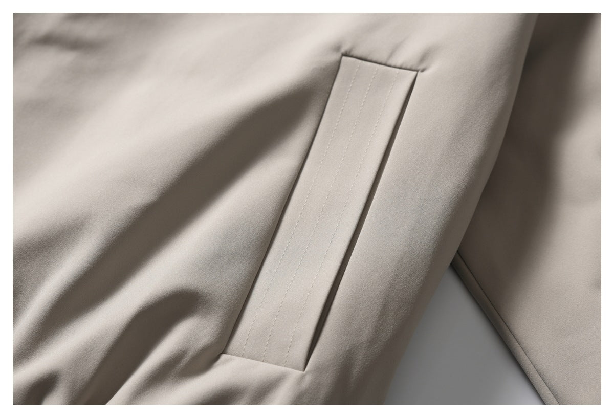 Close-up of a stitched pocket opening on taupe trousers.