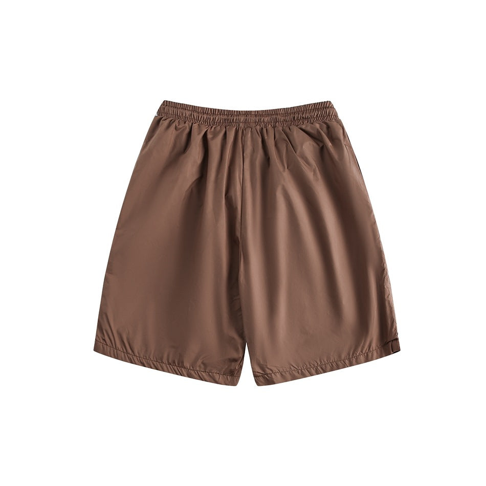 Front view of plain brown shorts with a gathered elastic waistband and wide legs on a white background.