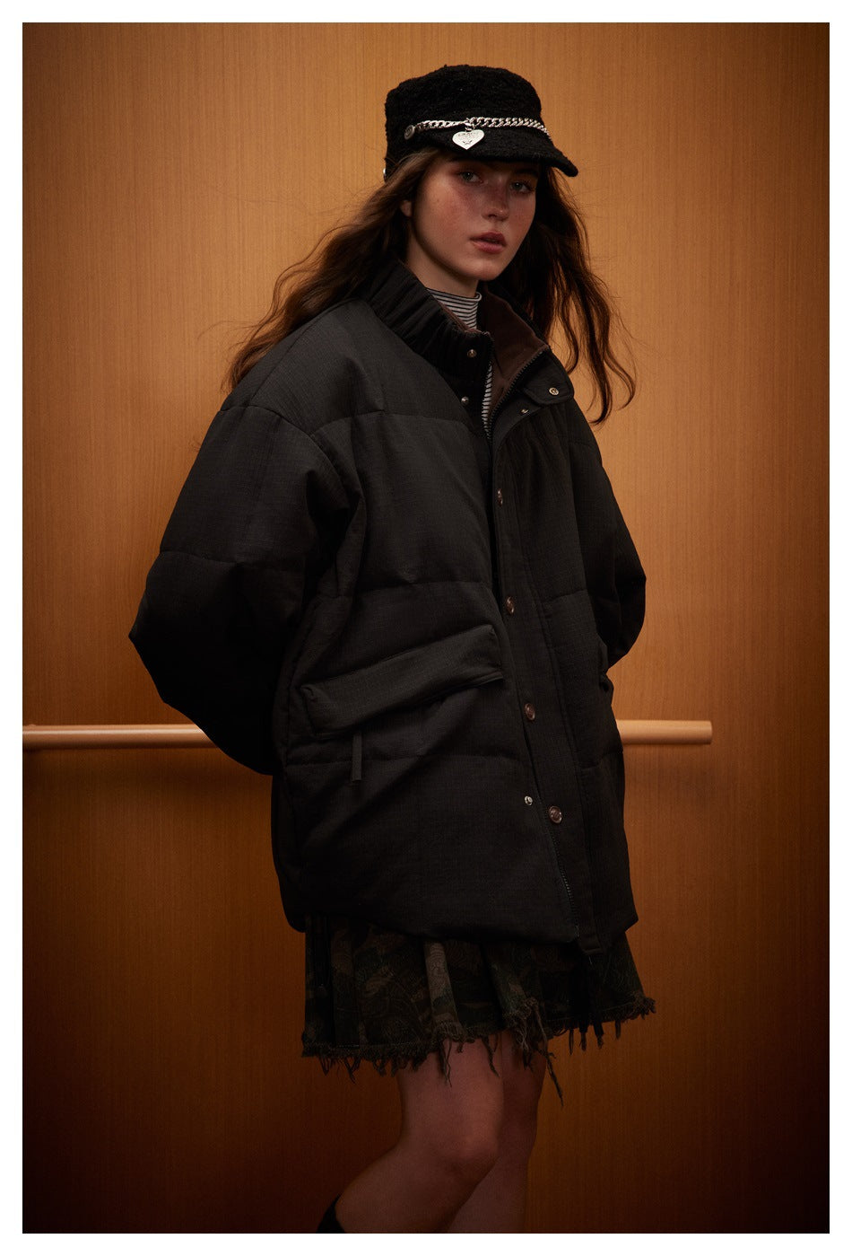 Three-quarter view of a model in a black quilted jacket with a high collar, snap closure and large flap pockets.