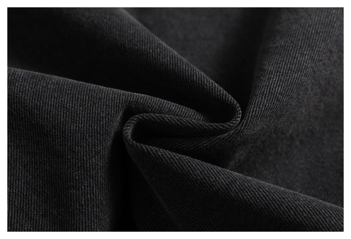 Close-up of black denim fabric folded to show its diagonal twill texture.