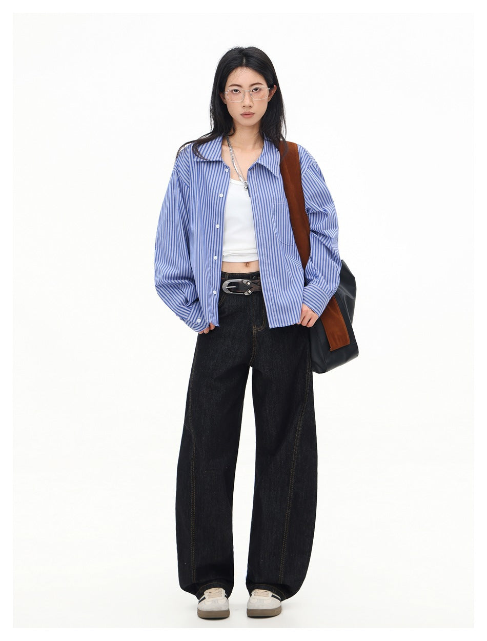 Model wearing the blue striped cropped shirt unbuttoned over a white top with dark jeans and a shoulder bag