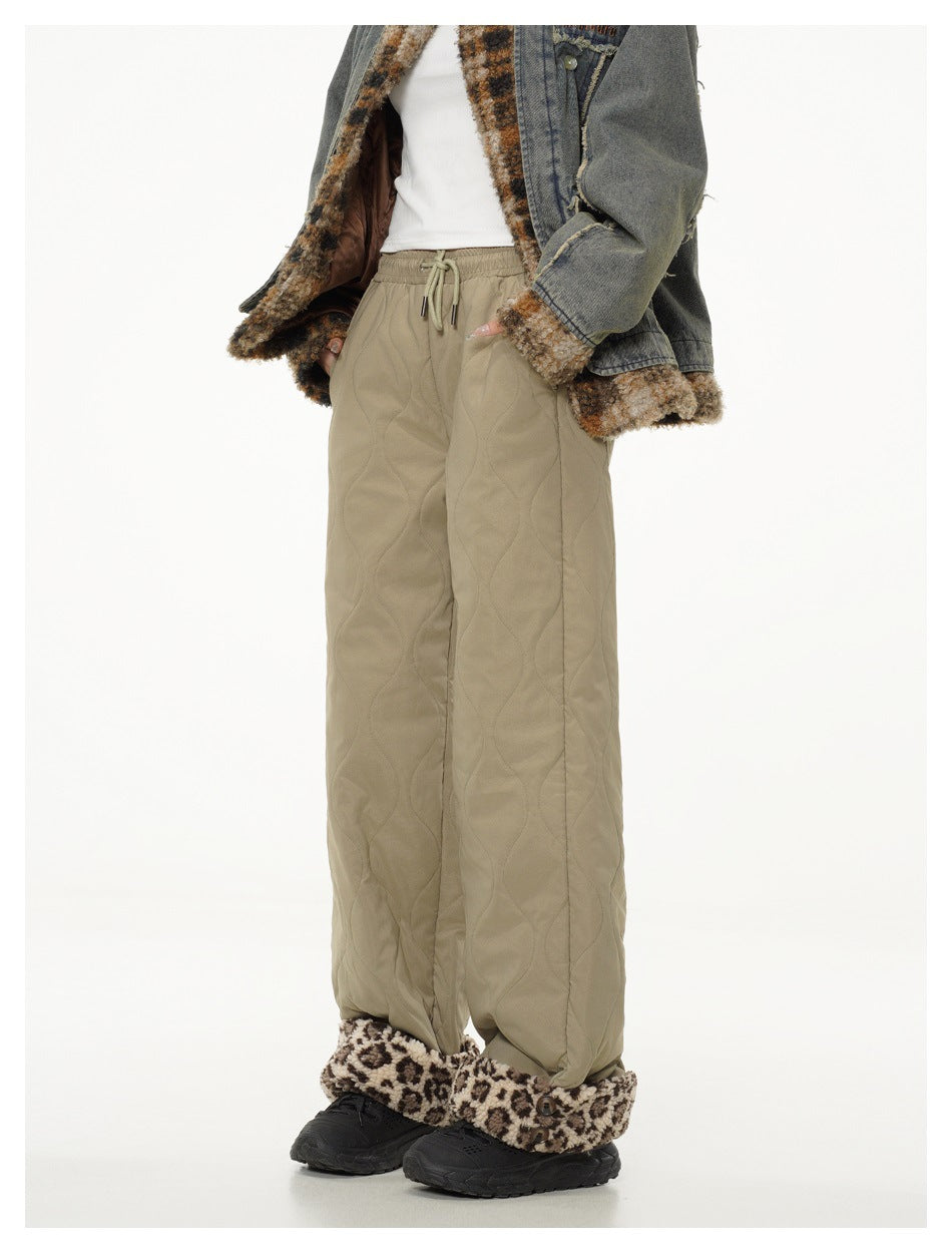 Model in khaki quilted wide-leg pants with a drawstring waist and brown patterned fleece cuffs, shown from a slight angle.