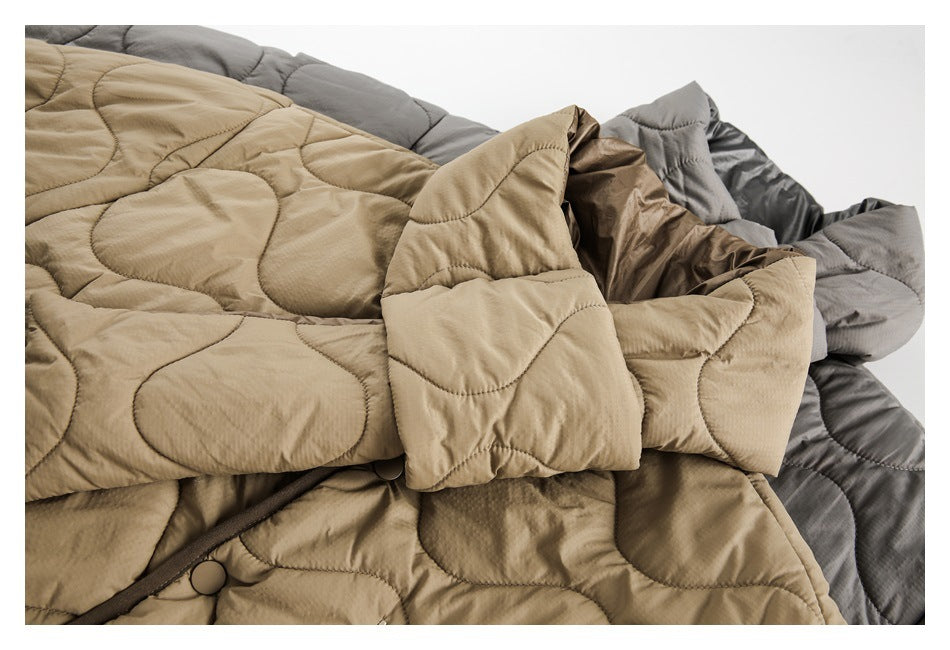 Close-up of beige and gray quilted jackets, showing wavy stitching, sleeves, and snap-button details.