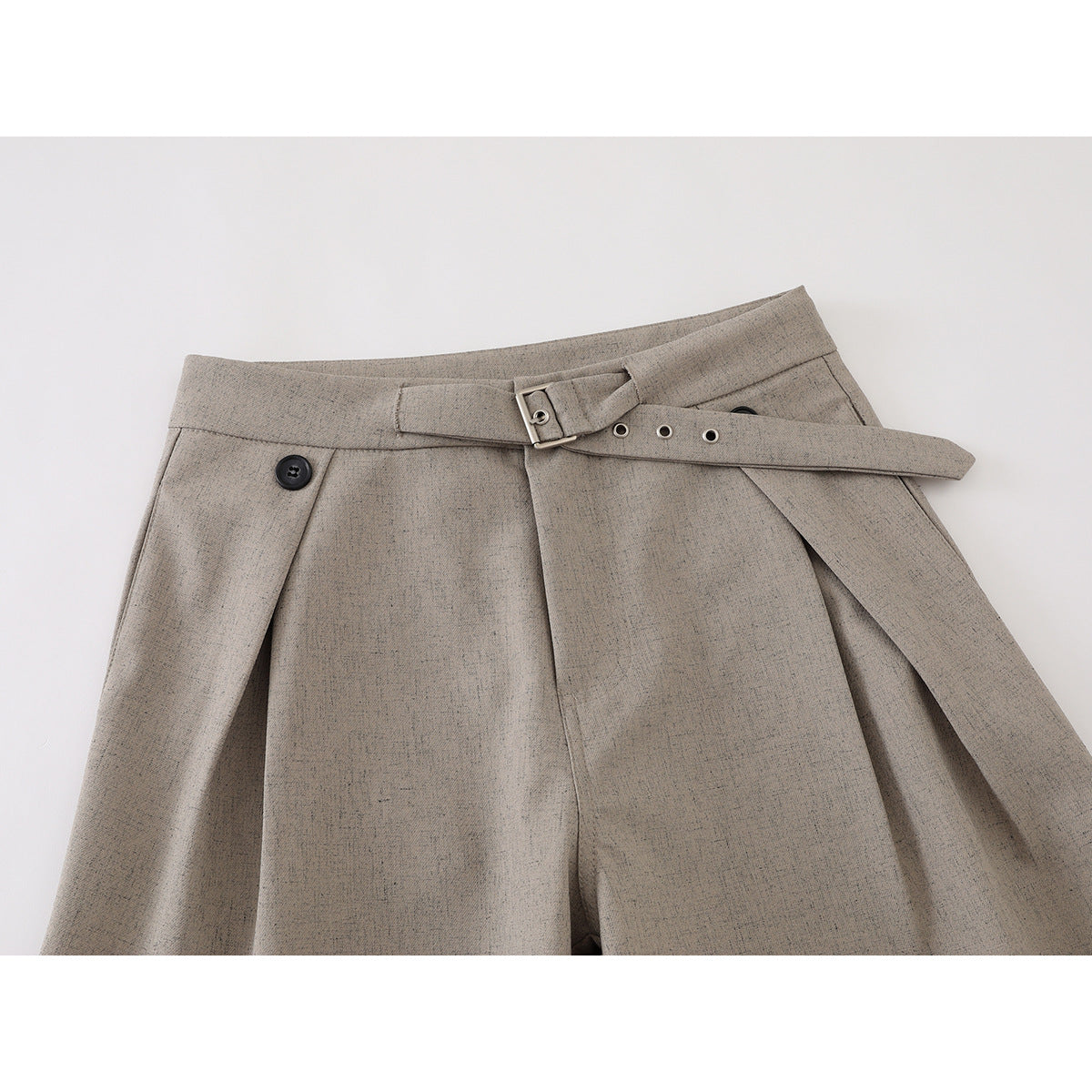 Close-up of taupe wide-leg trousers showing the waistband, button, and adjustable buckle belt.