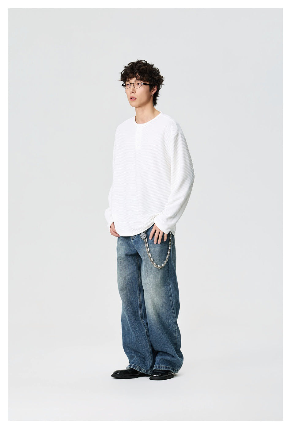 Model wearing a white ribbed long-sleeve henley with blue wide-leg jeans, shown full length.
