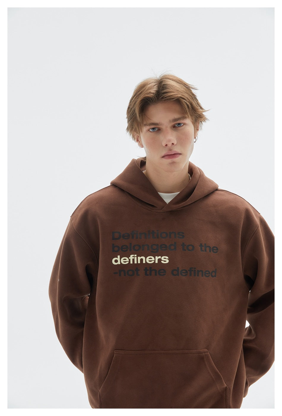 Close-up of a model wearing a brown hoodie with bold black and cream English text on the chest.