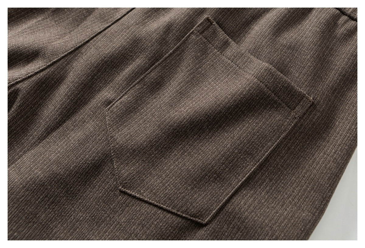 Close-up of a flap pocket and stitching on dark brown textured trousers.