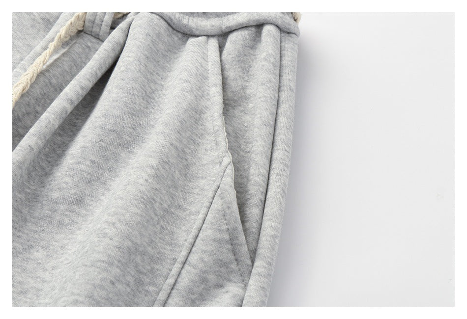 Close-up of a slanted side pocket and seam on light gray heathered sweatpants.