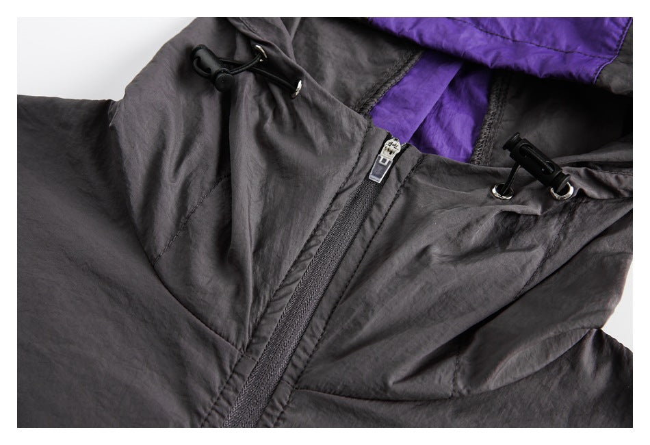 Close-up of a charcoal jacket hood with purple lining, a front zipper, and black drawcord toggles.