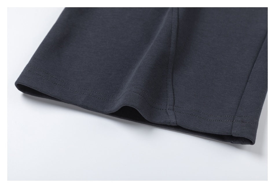 Close-up of the stitched hem and seam of charcoal pants.
