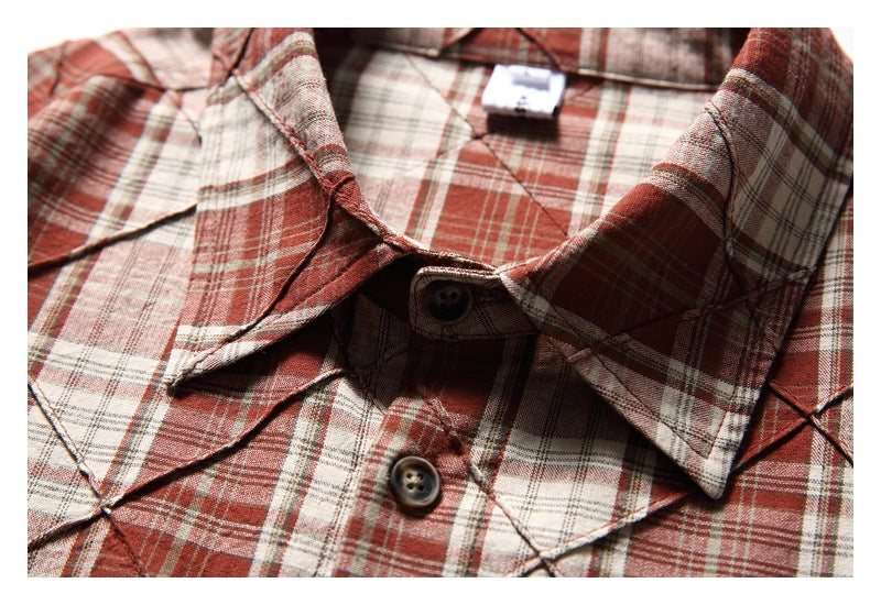 Close-up of the shirt’s pointed collar, dark buttons, and red, cream, and gray plaid pattern.