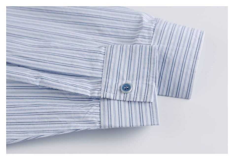 Close-up of a long-sleeve cuff with a blue button on a white shirt with thin blue stripes.