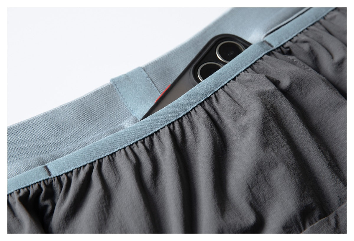 Close-up of the pale blue waistband and gathered charcoal fabric, with a phone tucked into the rear waistband pocket.