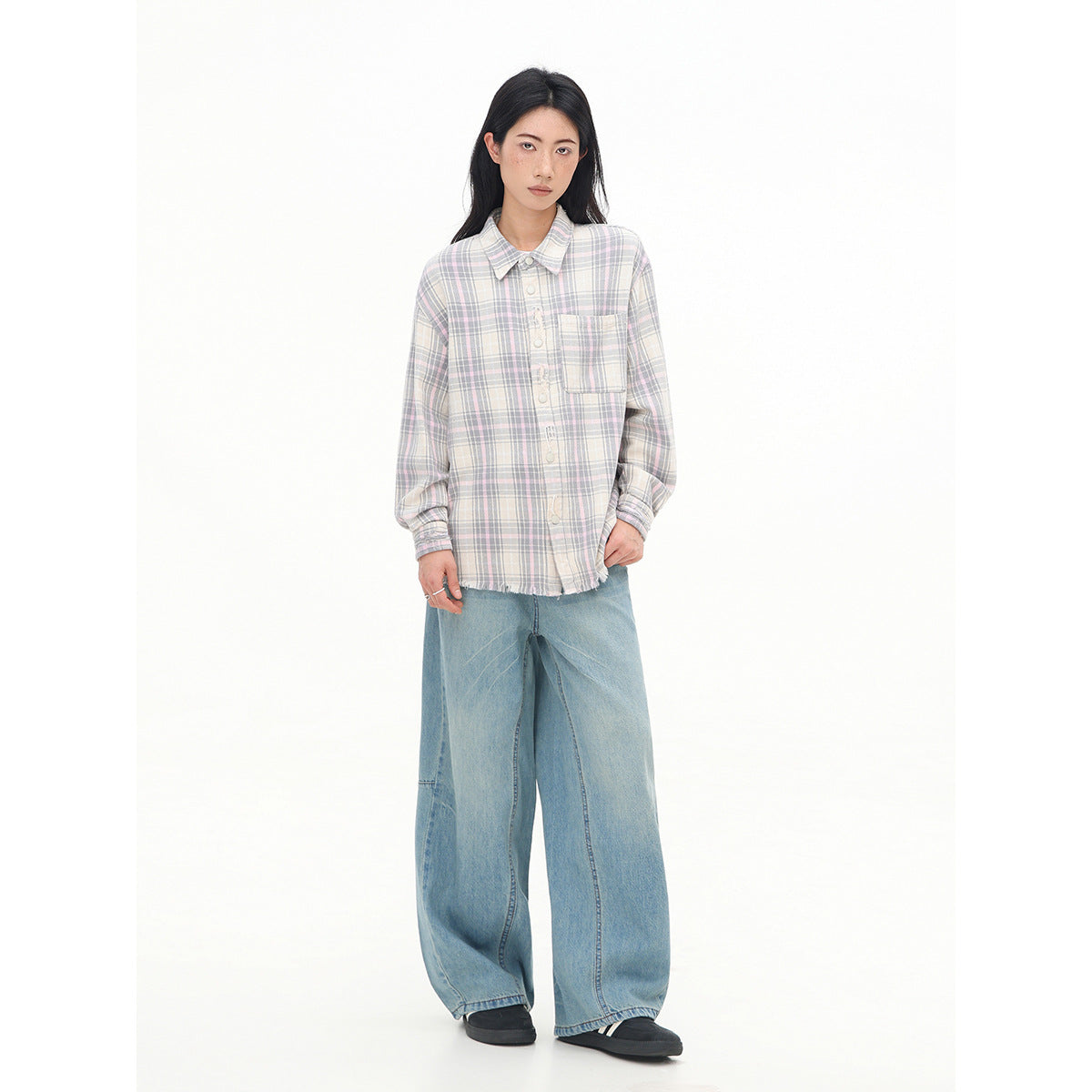 Model wearing a button-front shirt with a chest pocket in a muted pastel plaid, paired with wide-leg blue jeans.