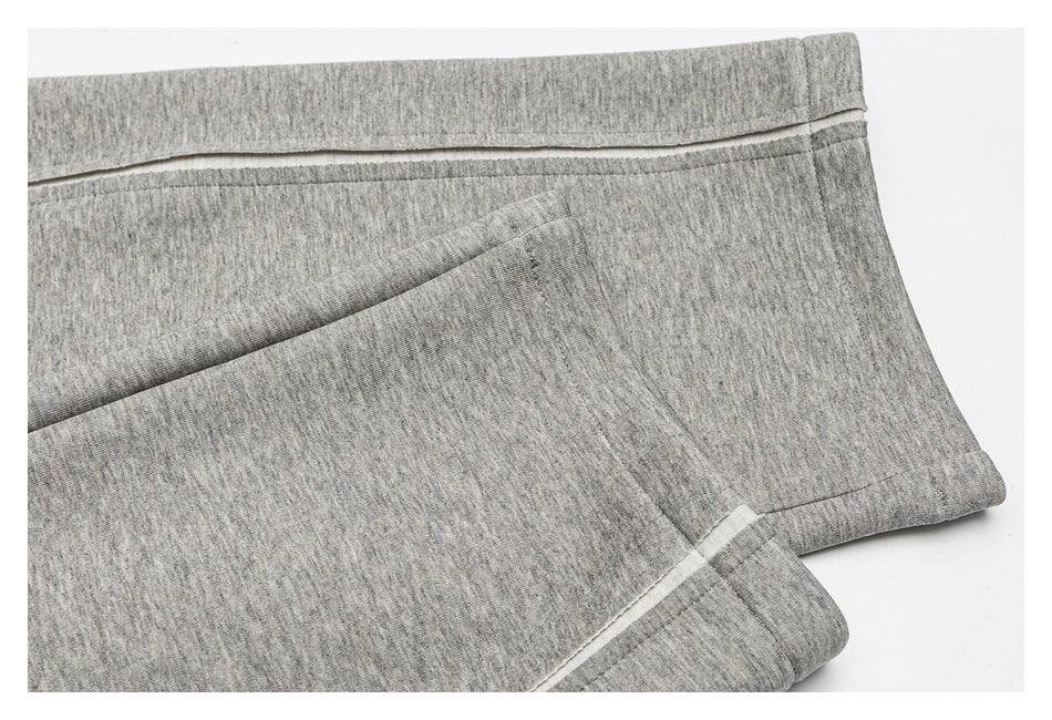 Close-up of gray heathered pant legs and stitched hems, with a narrow light-colored trim.