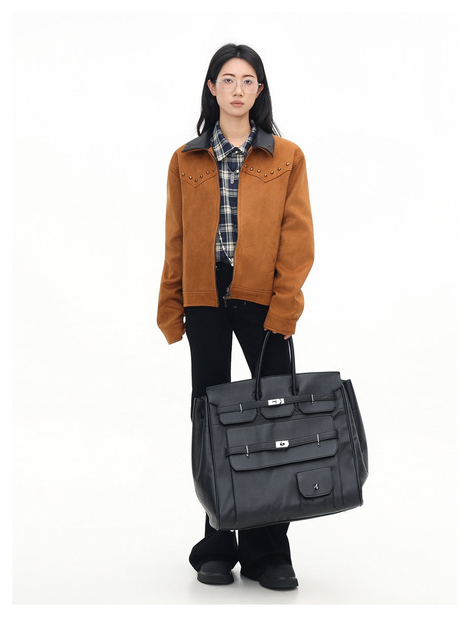 Model wearing a rust-brown jacket with a black collar and gold studs, styled with a plaid shirt and black trousers.