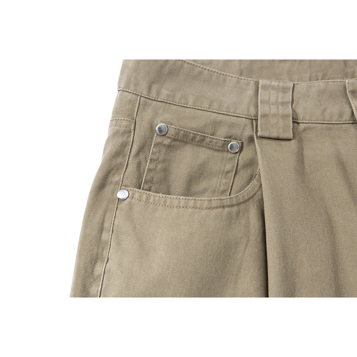 Close-up of tan shorts showing the waistband, belt loop, and front pocket with metal rivets.