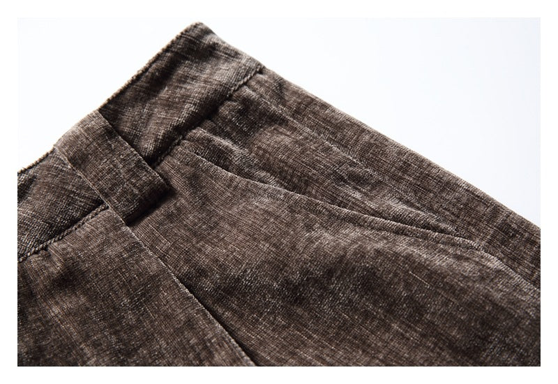 Close-up of a slanted front pocket and belt loop on brown trousers.